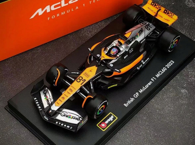 Maket makine F1 Bburago McLaren MCL60 2023 Oscar Piastri, shkalla 1:43, me helmetë, portokalli e zezë