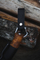 Mbajtëse thike Helle Black Buckle, lëkurë natyrale, karabiner çelik inoksi, e zezë
